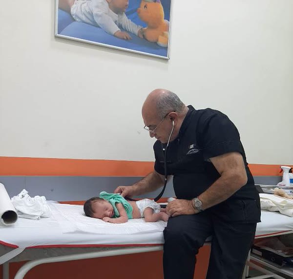 Dr. Sahib Cəfərov yenidoğulmuş körpəni stetoskopla müayinə edir